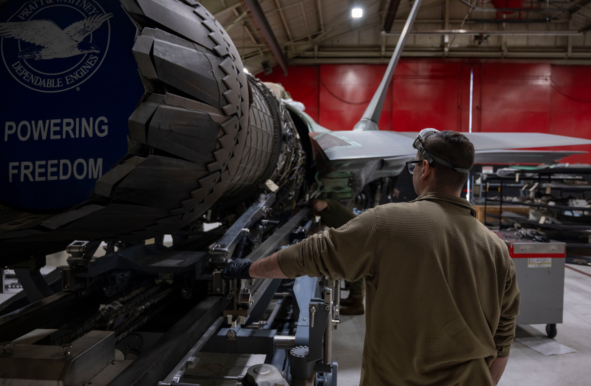 A photo of maintainers installing an engine into an F-35A Lightning II fighter jet.