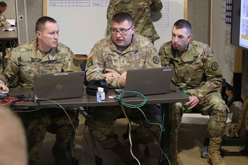 Three Soldiers train behind computers