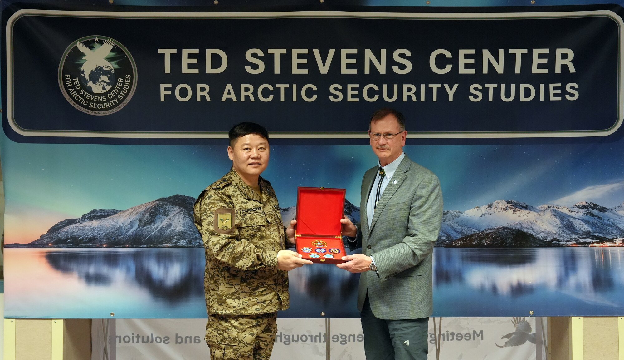 Col. T. Galbadrakh, deputy chief of the General Staff of the Mongolian Armed Forces, presents Randy Kee, director of the Ted Stevens Center for Arctic Security Studies, coins during a visit to the TSC on Joint Base Elmendorf-Richardson, Alaska, Feb. 14, 2024.