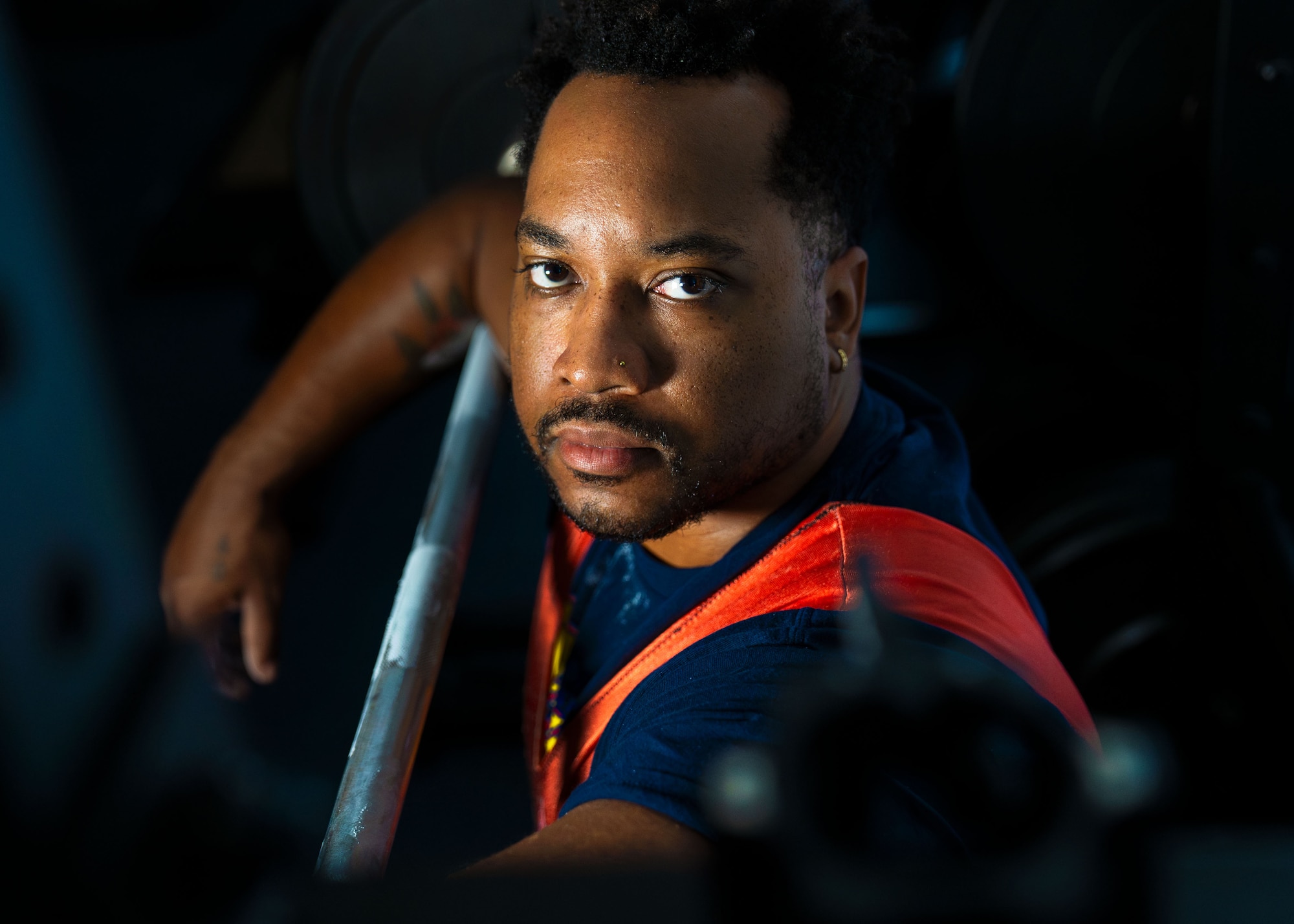 A man poses for a photo at a squat rack.