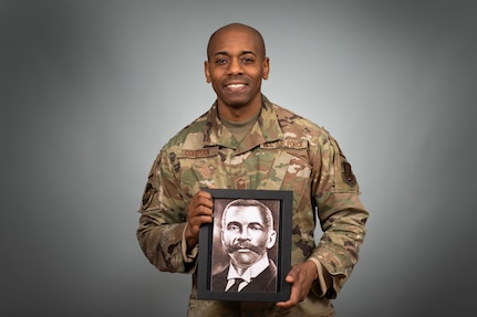 Photo of U.S. Air Force Master Sgt. Juan J. Coleman, 158th Fighter Wing traffic management specialist, holding a photograph of his great-great-great grandfather, Rev. Joe Berry Powell, at the Vermont Air National Guard Base, Feb. 21, 2024.