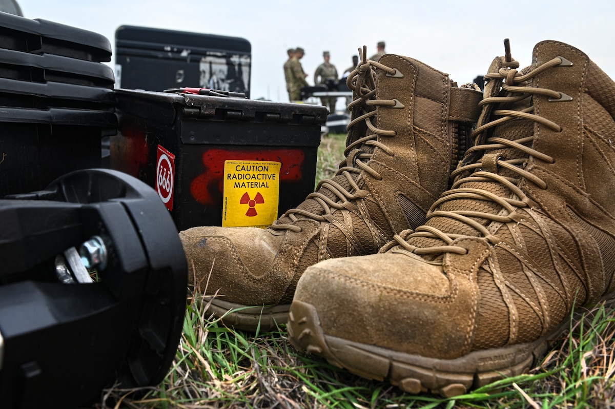 Different equipment and a pair of boots are pre-staged on the ground at a training site during a contingency exercise.