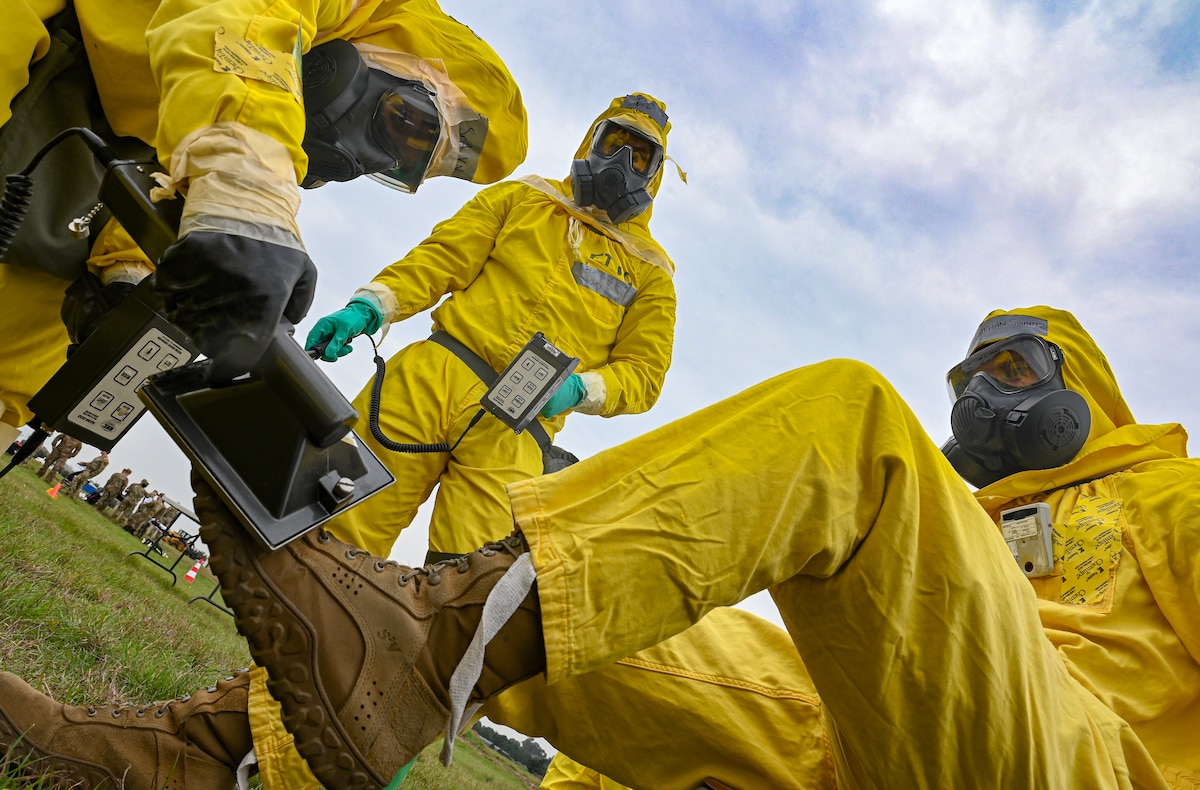 Two members of the 39th Civil Engineer Squadron Emergency Management support team simulate decontamination procedures on an Airman sitting down on the ground.