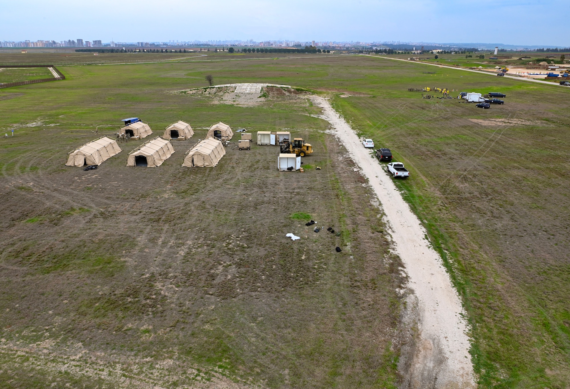 There are tents and tables in a field being used as a bed down site and contamination control stations during a contingency exercise.