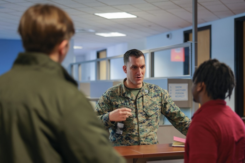 U.S. Marine Corps Gunnery Sgt. Joshua Ostermann, Prior Service Recruiting statistician chief, Marine Corps Recruiting Command and a native of El Cajon, Ca., center, has a conversation with Jackson Houser, Enterprise Service Desk technician, left, and Dante Parks, Enterprise Service Desk team lead, right, on Marine Corps Base Quantico Feb. 1, 2024. The ESD contractors provide general IT support and customer service to all of MCRC as well as recruiters around the country. (U.S. Marine Corps photo by Lance Cpl. Brenna Ritchie)