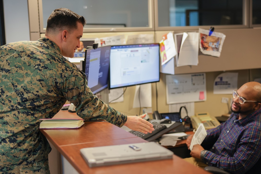 U.S. Marine Corps Gunnery Sgt. Joshua Ostermann, Prior Service Recruiting statistician chief, Marine Corps Recruiting Command and a native of El Cajon, Ca., left, shows Ammon Fasusi, Enterprise Service Desk technician, his Common Access Card during a conversation on Marine Corps Base Quantico Feb. 1, 2024.The ESD contractors provide general IT support and customer service to all of MCRC as well as recruiters around the country. (.U.S. Marine Corps photo by Lance Cpl. Brenna Ritchie)