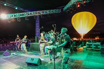 The 39th Army Band, 54th Troop Command, New Hampshire Army National Guard, plays with a hot air balloon pulsing flames at the Ilopango Air Show in El Salvador on Feb. 18, 2024.