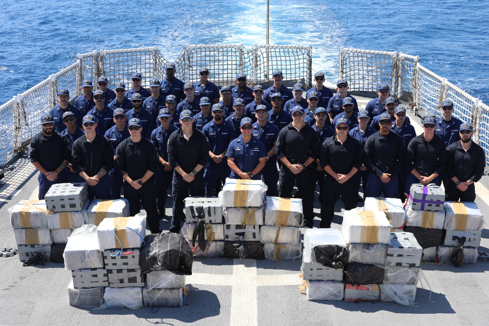 The crew of U.S. Coast Guard Cutter Reliance (WMEC 615) poses for a photo in front of approximately $52 million in illicit narcotics on the cutter’s flight deck in the Eastern Pacific Ocean, Feb. 13, 2024. Patrolling in support of Joint Interagency Task Force-South, the Reliance crew stopped two drug trafficking ventures, detaining six suspected traffickers and preventing nearly 4,000 pounds of cocaine, and 5,400 pounds of marijuana, worth more than $57 million, from entering the United States. (U.S. Coast Guard photo courtesy of Reliance)