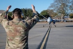 A man in a uniform has his arms in the air, directing a remotely piloted aircraft.