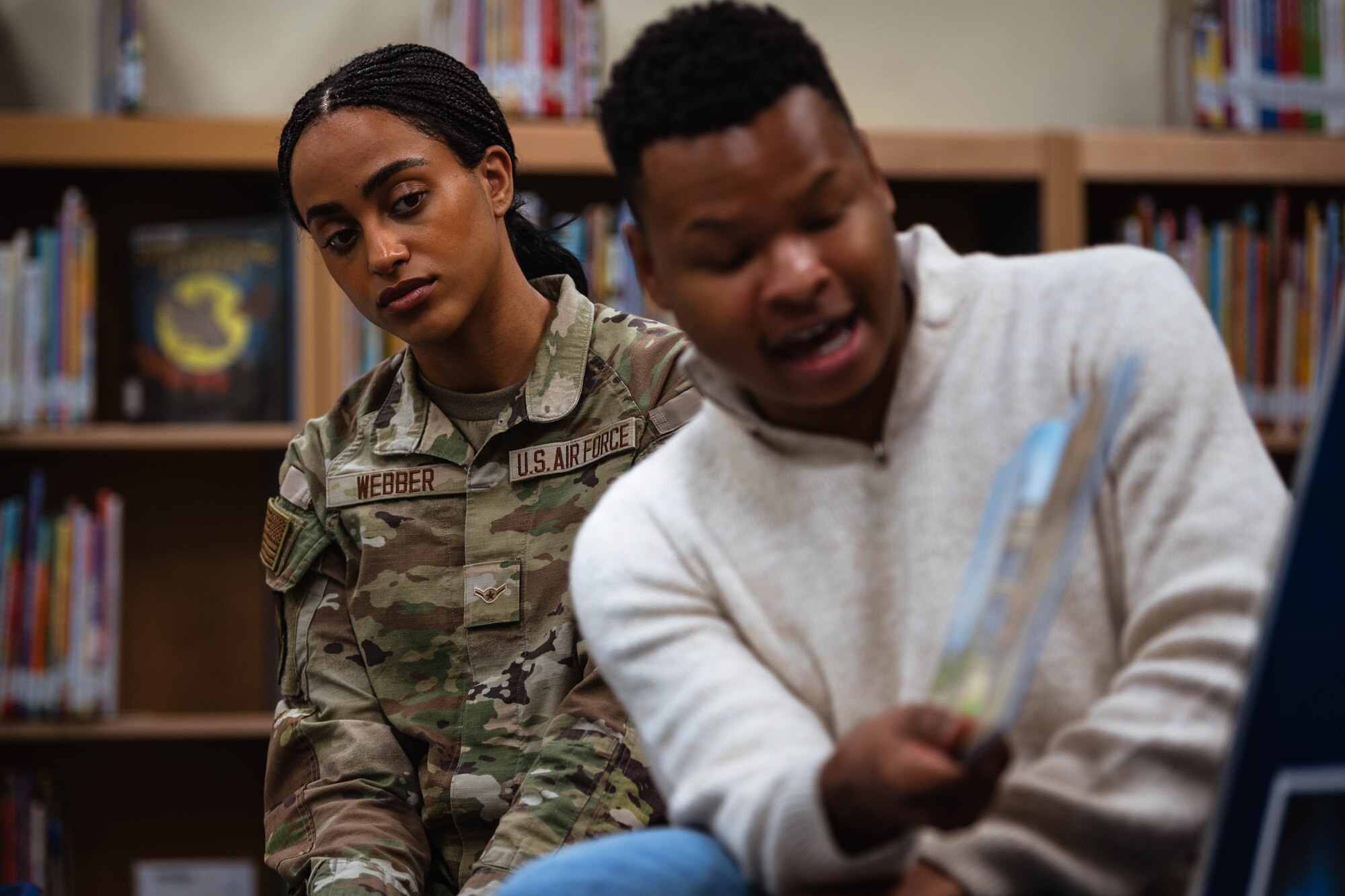 U.S. Air Force Airman Sheyenne Webber, 56th Judge Advocate military justice paralegal, listens as Staff Sgt. Reginald Dean, 56th Component Maintenance Squadron weapon systems coordinator, reads to children and their parents during a Black History Month story-time event at the base library.