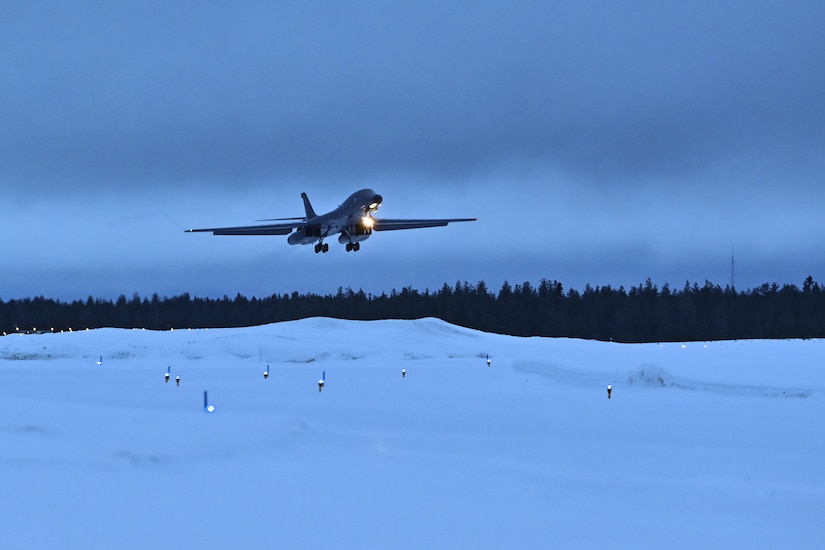 A lancer approaches a runway for a snowy landing with trees in the backdrop.