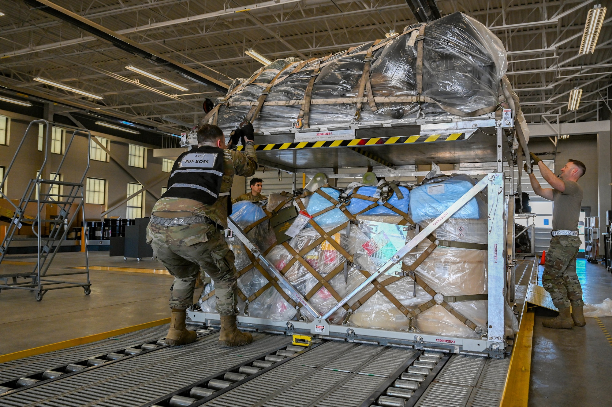 Members from the 28th Logistics Readiness Squadron secure cargo netting onto a vertically stacked cargo unit, at Ellsworth Air Force Base, South Dakota, Feb. 19, 2024. In preparation for a Bomber Task Force mission to Sweden, the 28th LRS coordinated with the 758th Airlift Squadron to implement and execute vertical pallet stacking in order to maximize cargo space. (U.S. Air Force photo by Airman 1st Class Dylan Maher)
