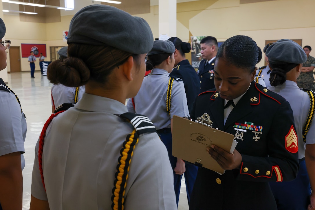 U.S. Marine Corps Sgt. Andrea Rosembert, the administrative non-commissioned officer for Marine Corps Base Camp Blaz, grades a student from Southern High School’s Junior Reserve Officers’ Training Corps program during their inspection as part of an island-wide JROTC drill meet in Dededo, Guam, Feb. 17, 2024. Okkodo High School held the drill competition with active duty service members serving as judges to evaluate each school’s performance in unarmed, armed, and color guard competitions with both regulation and exhibition routines. (U.S. Marine Corps photo by Lance Cpl. Ryan Little)
