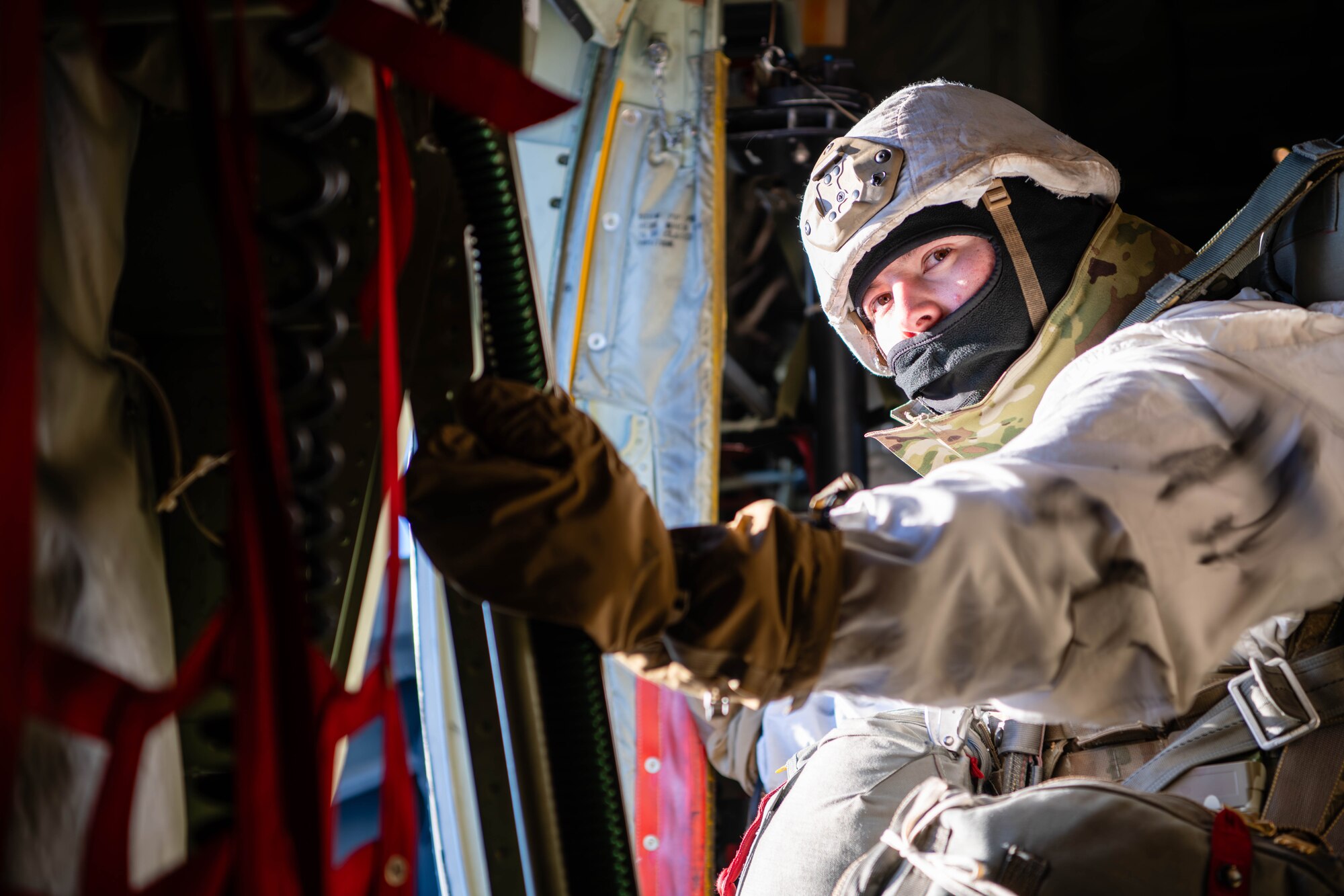 A paratrooper from the U.S. Army 2nd Infantry Brigade Combat Team, 11th Airborne Division, prepares to jump out of a C-130J Super Hercules as part of a joint forcible entry exercise during Joint Pacific Multinational Readiness Center 24-02 in Alaska.