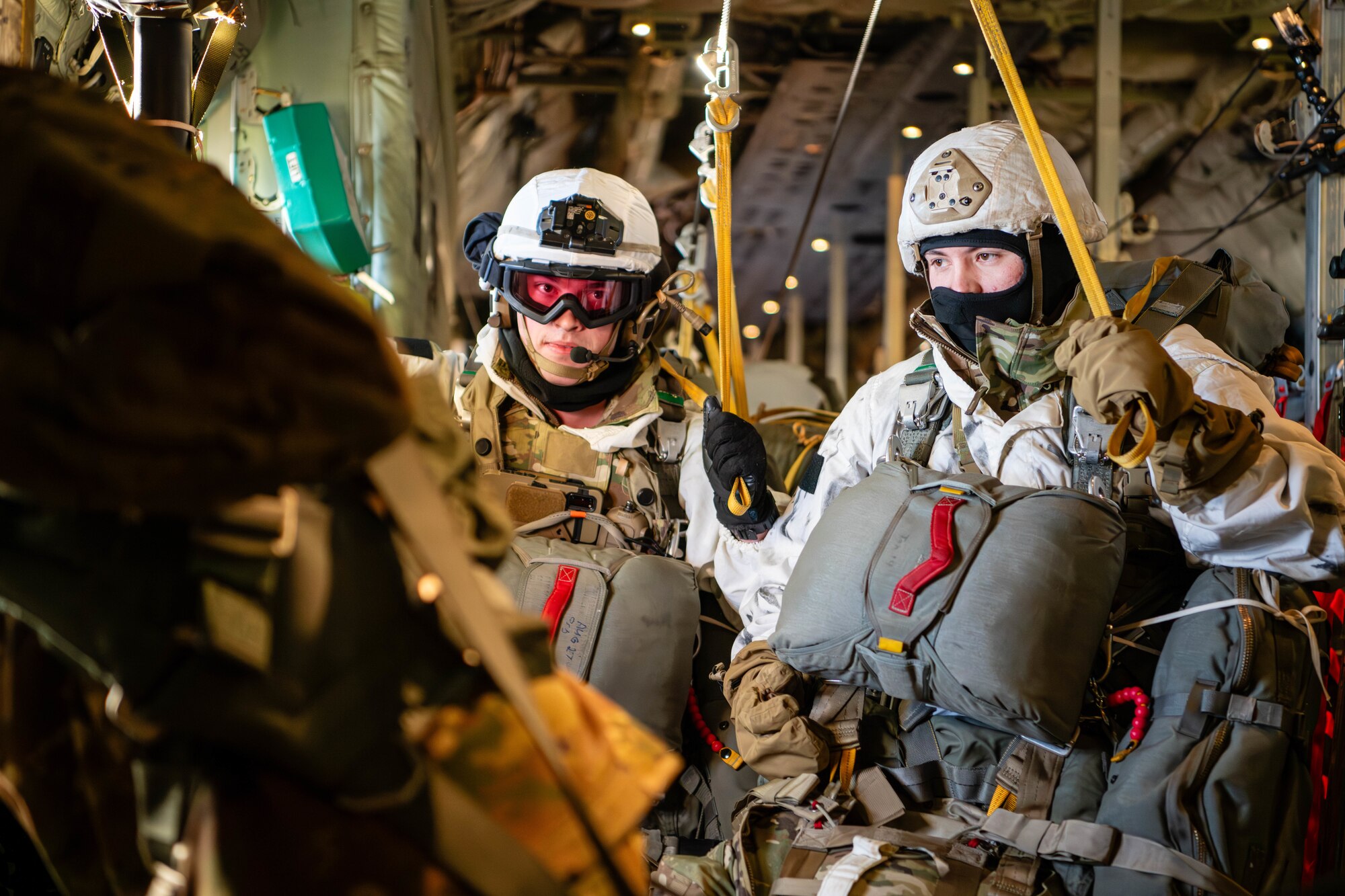Paratroopers from the U.S. Army 2nd Infantry Brigade Combat Team, 11th Airborne Division, hold onto static lines inside of a C-130J Super Hercules prior to conducting an airborne assault as part of a joint forcible entry exercise during Joint Pacific Multinational Readiness Center 24-02 in Alaska.
