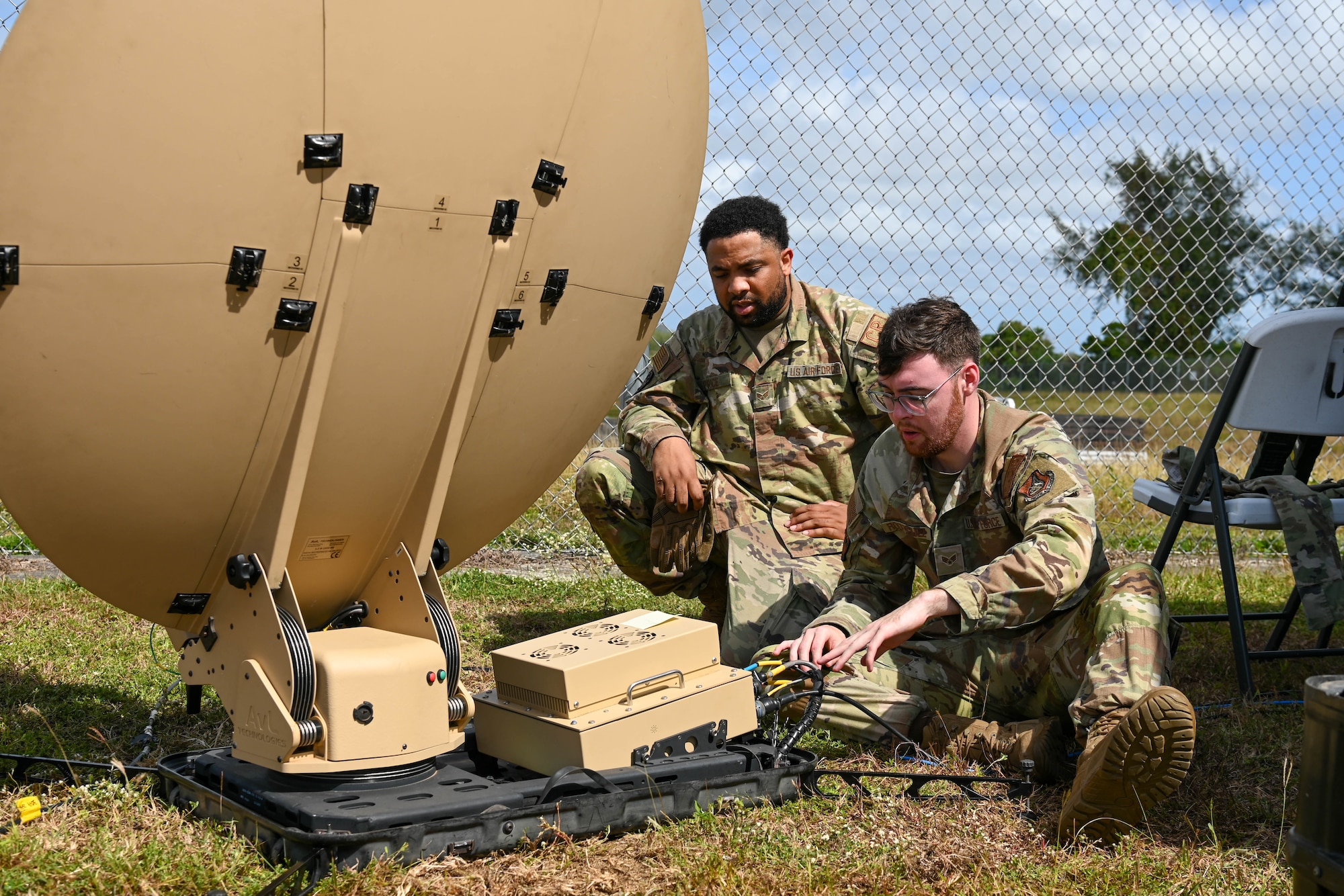 U.S. Air Force Senior Airman Jay Price, radio frequency transmission systems technician with the 644th Combat Communications Squadron and Senior Airman Gregory Rodriguez, radio frequency transmissions systems technician with the 18th Communications Squadron, set up part of a tactical communications kit on the Island of Tinian, Feb. 10, 2024. The 18th CS from Kadena Air Force Base, Japan and the 644th CBCS from Andersen Air Force Base, Guam worked together alongside the Royal Australian Air Force and Japanese Air Self-Defense Force using the trilateral C2 network from a United States Air Force tactical comm kit on the Island of Tinian during Cope North 24. (U.S. Air Force photo by Senior Airman Allison Martin)