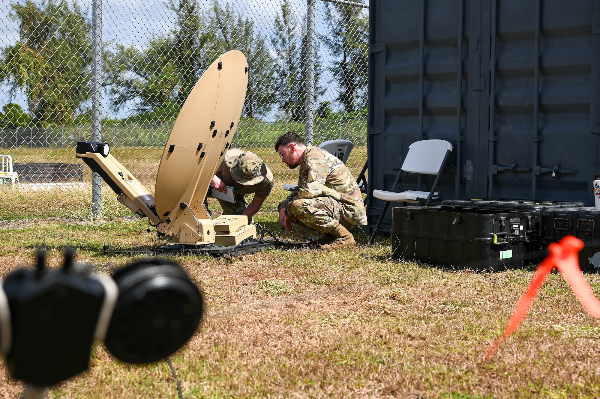 U.S. Air Force Senior Airman Jay Price, radio frequency transmission systems technician with the 644th Combat Communications Squadron and Senior Airman Gregory Rodriguez, radio frequency transmissions systems technician with the 18th Communications Squadron, set up part of a tactical communications kit on the Island of Tinian, Feb. 10, 2024. The 18th CS from Kadena Air Force Base, Japan and the 644th CBCS from Andersen Air Force Base, Guam worked together alongside the Royal Australian Air Force and Japanese Air Self-Defense Force using the trilateral C2 network from a United States Air Force tactical comm kit on the Island of Tinian during Cope North 24. (U.S. Air Force photo by Senior Airman Allison Martin)