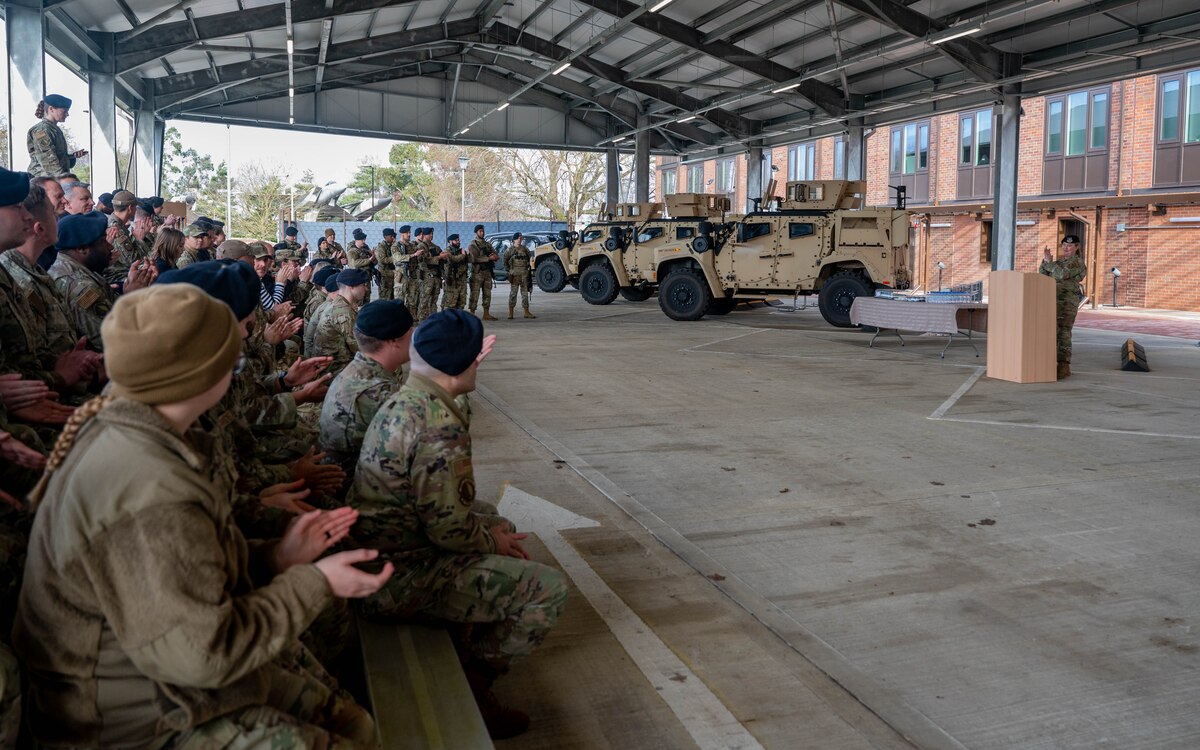 A crowd of U.S. military members clap their hands during an event.