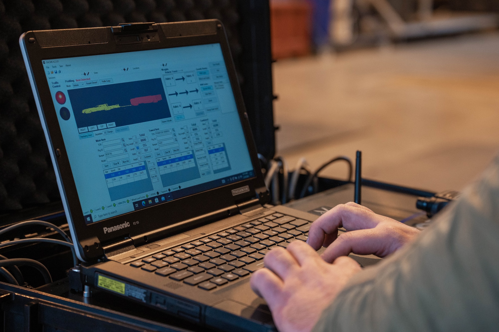 A U.S. military members types on a computer while processing cargo