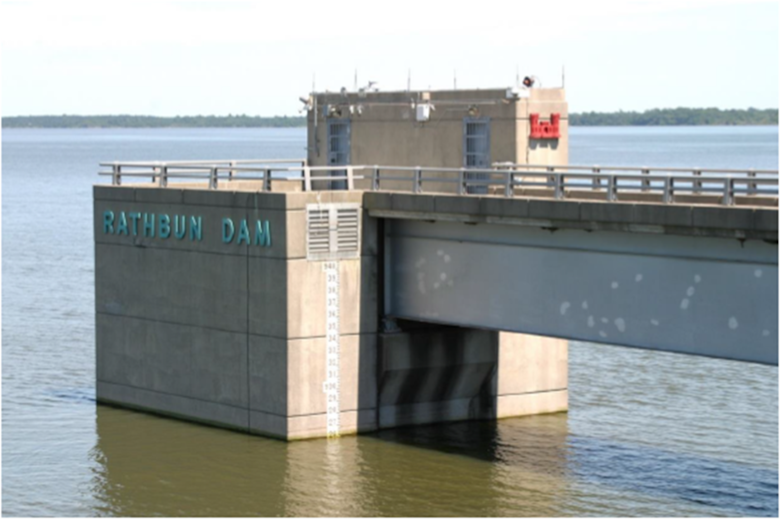 A concrete structure sits in water with sky in the background.