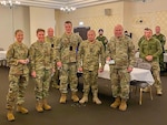 Army Sgt. Iuliia Nichols (second from the left), a culinary specialist assigned to the Florida Army National Guard’s 927th Combat Sustainment Support Battalion, has just received Ukraine’s Commander-in-Chief Award for her contributions in training Ukrainian soldiers. Ukrainian army Maj. Gen. Oleksiy Taran (second from the right, foreground), head of the Main Department of Doctrine and Training of the General Staff of the Armed Forces of Ukraine, presented Nichols with this honor at an awards ceremony during the Joint Training Conference in Wiesbaden, Germany, December 2023. Nichols has used her linguistic skills speaking Russian, Ukrainian and English to serve as an interpreter to facilitate the training of Ukrainian forces, support senior officers, and perform as a diplomatic escort. Note: This image has been altered for operational security reasons. (Photo courtesy of 1st Lt. Maxim Kargin.)