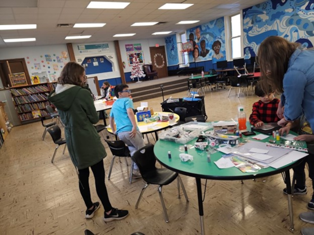 Children standing in classroom with colorful art on the walls.