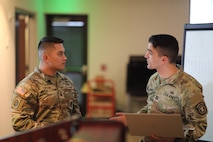 two men wearing u.s. army uniforms standing at the front of the group talking to each other.