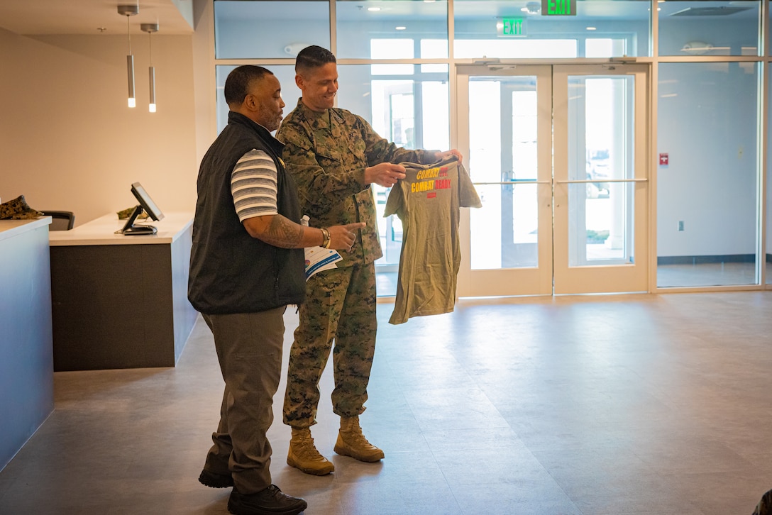 Raymond E. Anderson, left, director of strength and conditioning with Marine Corps Community Services, gives U.S. Marine Corps Sgt. Maj. Carlos A. Ruiz, Sergeant Major of the Marine Corps, a shirt in the future Warrior Athlete Readiness and Resilience Center, currently under construction, on Marine Corps Base Camp Lejeune, North Carolina, Feb. 22, 2024. This facility will house a holistic, collaborative program that will enhance combat readiness in conjunction with warfighter resiliency by strengthening the mental, social, spiritual, and physical fitness necessary to overcome any challenge. (U.S. Marine Corps photo by Lance Cpl. Loriann Dauscher)