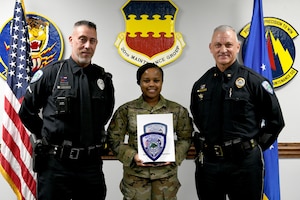 Two police officers present a military member with an award.
