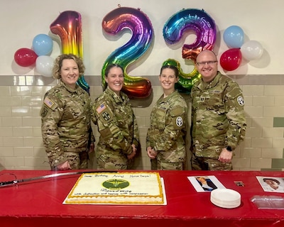 Four Army Nurse Corps Officers standing in front of a birthday cake celebrating the ANC Birthday