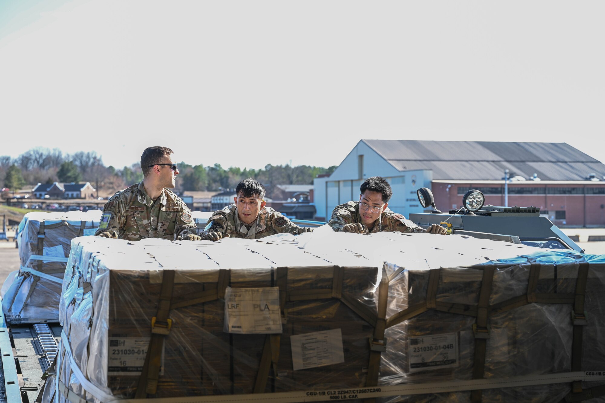 Men in uniform push cargo onto an aircraft