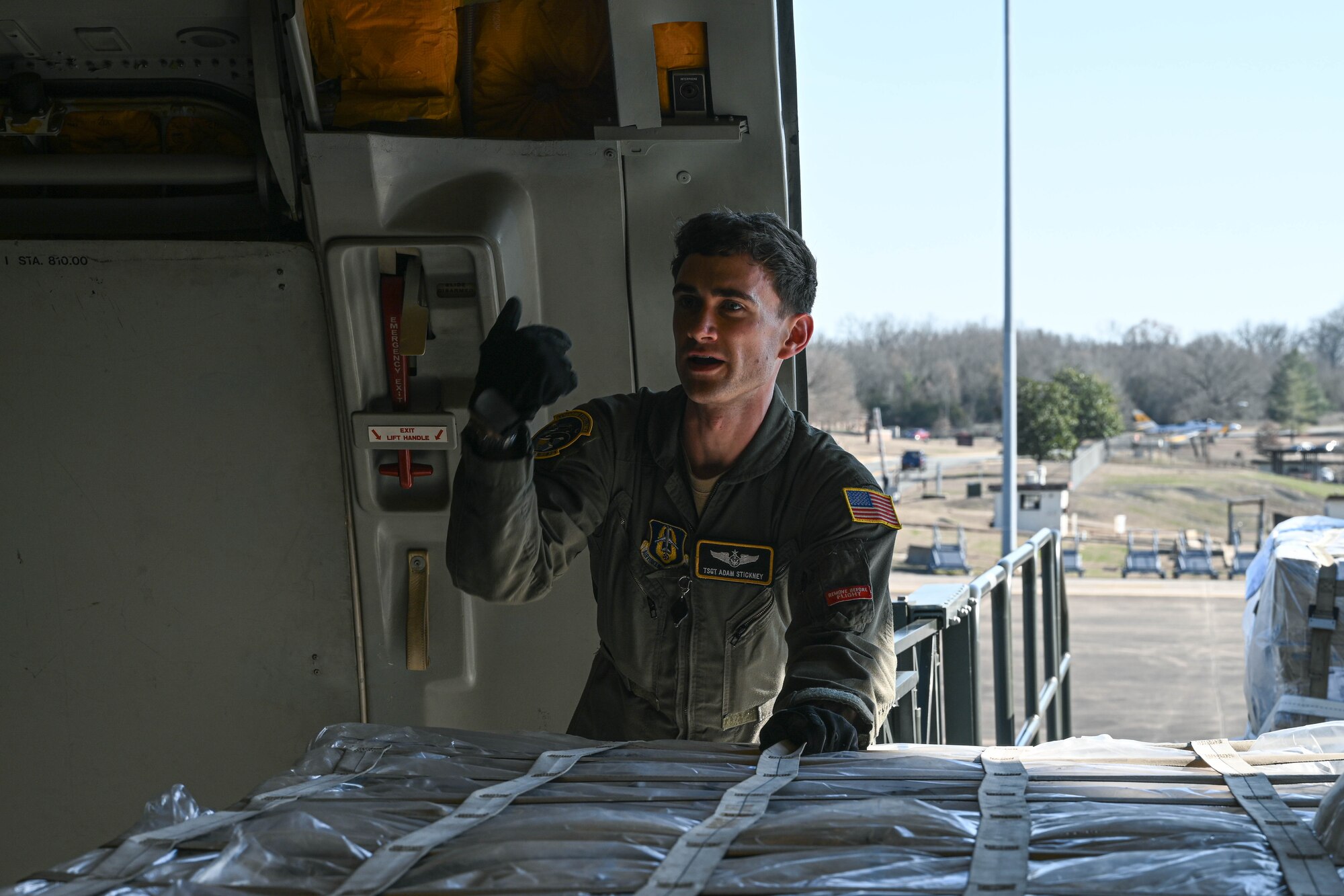 A man in uniform stands leaning over cargo