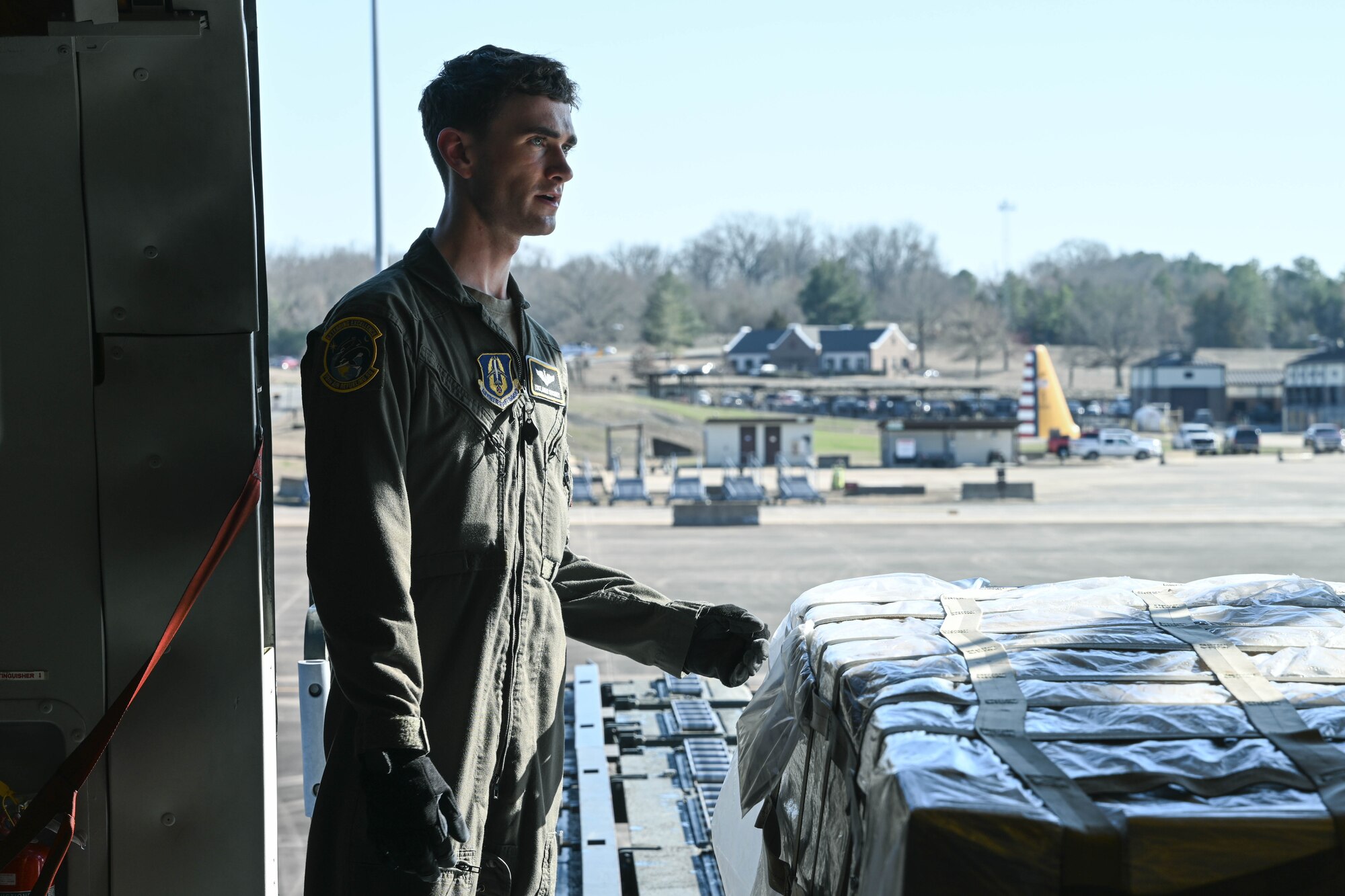 A man in uniform stands next to cargo