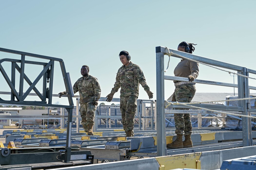 A group of people in uniform stand and watch a truck drive away