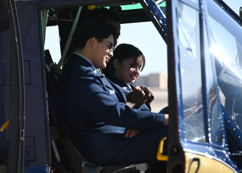 Two high school students sit in the cockpit of a helicopter.