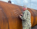 240224-N-MJ402-3507 PEARL HARBOR, Hawaii - Pearl Harbor Naval Shipyard and Intermediate Maintenance Facility (PHNSY & IMF) Commander Capt. Richard Jones signs a pile that will anchor the foundational footprint of Dry Dock 5 at PHNSY & IMF. This is the first graving dock built in Pearl Harbor since 1943 and the highest-value single construction project in the history of the Navy. The new dry dock will enhance PHNSY & IMF’s mission to repair, maintain, and modernize Navy fast-attack submarines and surface ships, keeping them Fit to Fight. Capt. Jones is pictured writing, “Dry Dock 5 will carry the shipyard well into the next century, enabling our Shipyard ‘Ohana to fulfill the mission of keeping our Fleet ‘Fit to Fight’ for generations to come.” U.S. Navy photo by Lauren Matakas