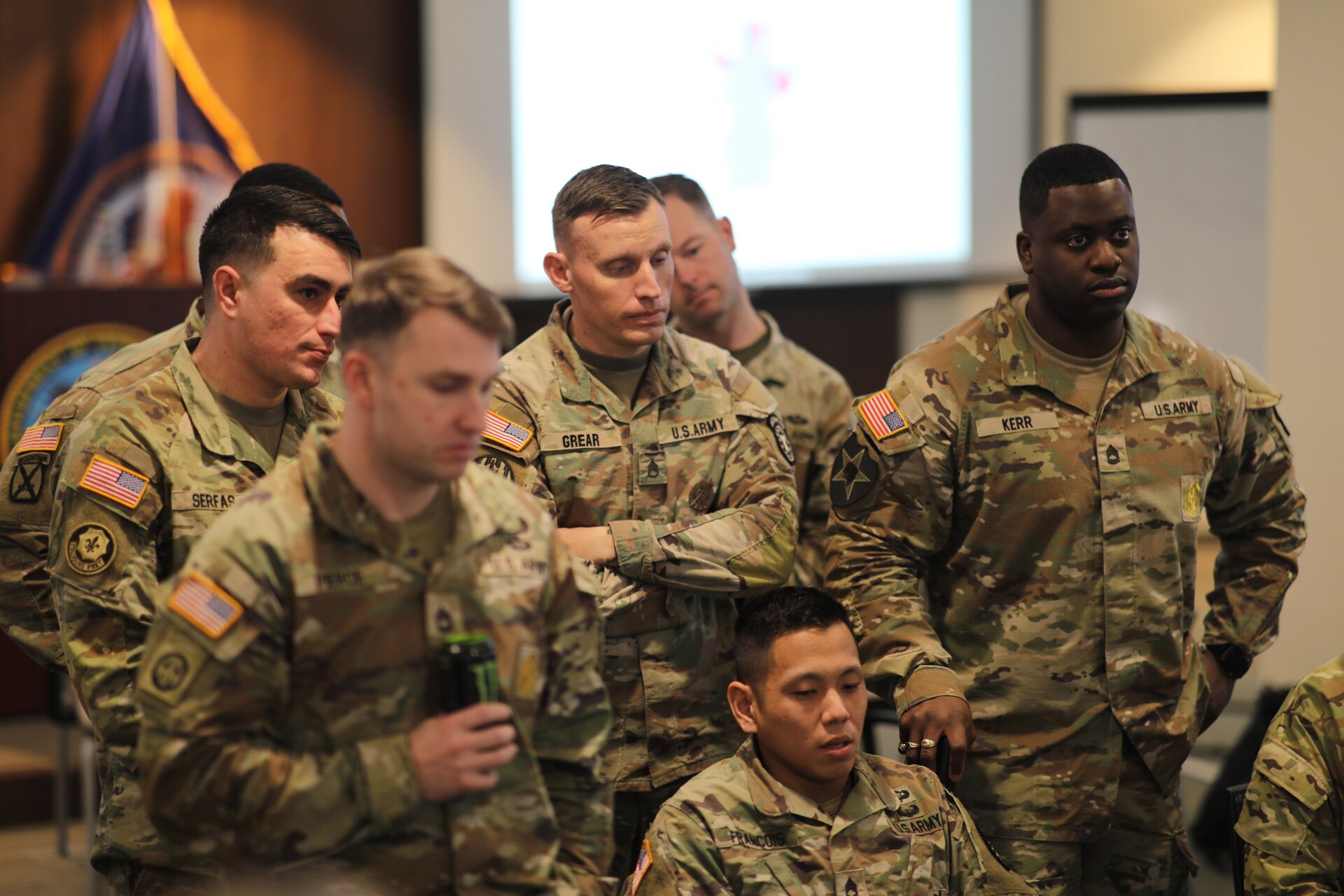 group of men wearing u.s. army uniform standing and listening.