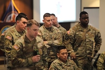 group of men wearing u.s. army uniform standing and listening.