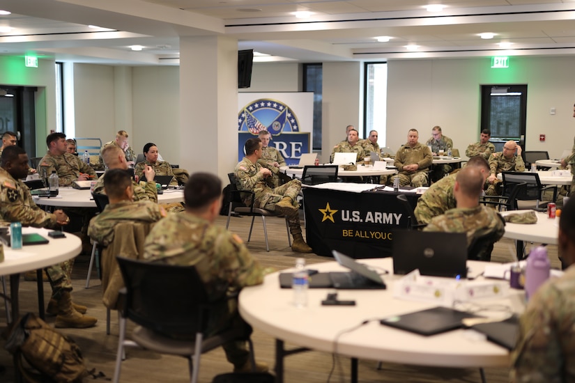 group of people wearing u.s. army uniforms sit in groups in an office.