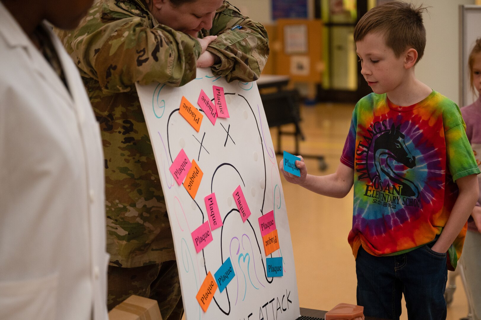 U.S. Air Force Senior Airman Terra Thomas, 51st Medical Group dental assistant, left, and Capt. Theresa Ten-Haaf, general dentist, middle, host dental hygiene themed games for Osan Elementary School students at Osan Air Base, Republic of Korea, Feb. 23, 2024. Airmen assigned to the 51st Medical Group dental clinic visited the school for National Children’s Dental Health Month. They conducted lessons on dental health and ended the session with interactive games and prizes. (U.S. Air Force photo by Senior Airman Brittany Russell)