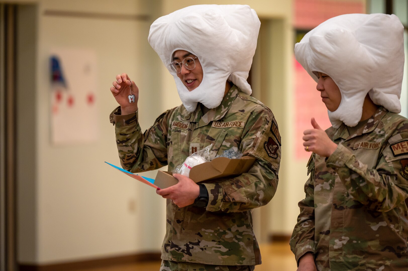 U.S. Air Force Capt. John Namgoong, 51st Medical Group general dentist, left, and Senior Airman Kyna Phimphrachanh, dental assistant, pass out prizes to Osan Elementary School students at Osan Air Base, Republic of Korea, Feb. 23, 2024. The Airmen visited the school to bring awareness to National Children’s Dental Health Month. They hosted games and passed out prizes to make learning about dental hygiene a fun and interactive experience for the children.  (U.S. Air Force photo by Senior Airman Brittany Russell)