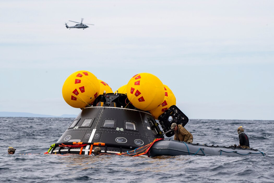 Navy divers from EODMU-1 inflate a life raft during Underway Recovery Test 11 in the Pacific Ocean.