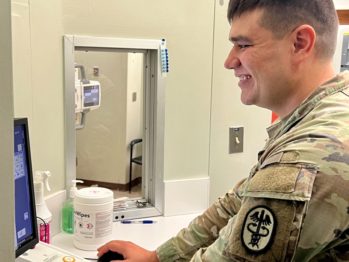 Smiling Soldier looking at a computer screen.