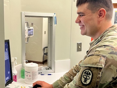 Smiling Soldier looking at a computer screen.