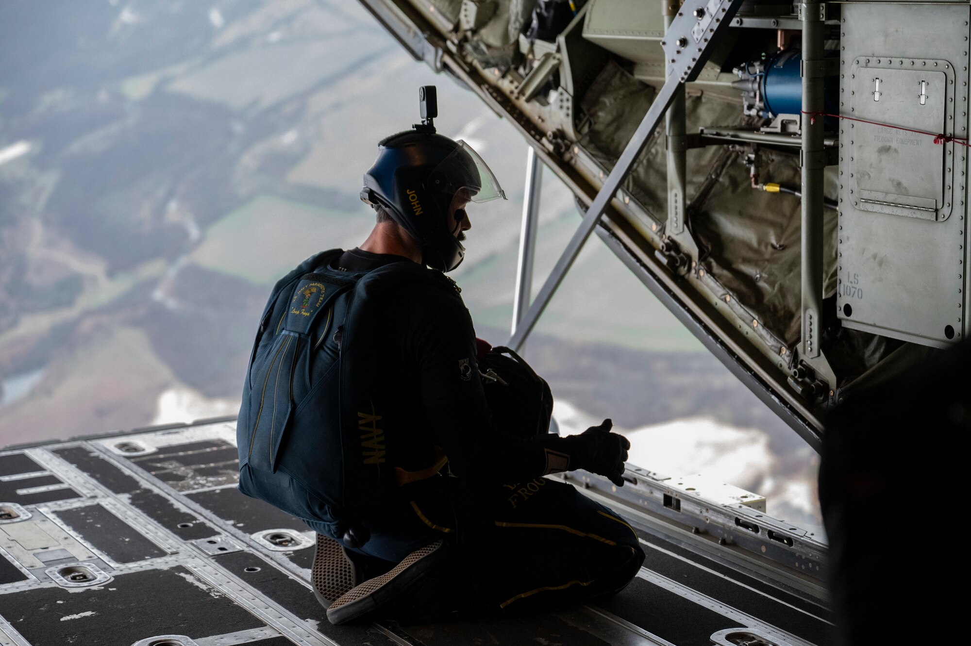A U.S. Navy Parachute Team member looks out of a C-130J Super Hercules in Texas, Feb. 10, 2023. The 317th Airlift Wing provided airlift support to the team, completing key training objectives and demonstrating joint interoperability. The Navy Parachute Team began in 1969 when Navy SEALs and Underwater Demolition Team (UDT) members volunteered at weekend air shows. The team was officially commissioned the Leap Frogs in 1974 by the Chief of Naval Operations with the mission to demonstrate Navy excellence throughout the United States. (U.S. Air Force photo by Airman 1st Class Emma Anderson)