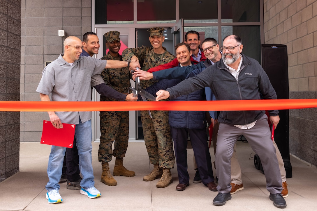 U.S. Marine Corps Col. William Osborne, commanding officer of I Marine Expeditionary Force Information Group, Sgt. Maj. Theodore G. Ingram III, sergeant major of I MIG, and civilian employees who worked on the new I MIG Headquarters building cut a ribbon during the I MIG ribbon-cutting ceremony on Camp Pendleton, California, Feb. 26, 2024. I MIG Marines held the ribbon-cutting ceremony to commemorate their lineage and celebrate the opening of the new headquarters command post, Hammer Hall. The building, taking over 387,000 manpower hours to complete, is outfitted with numerous technological additions exclusive to I MIG HQ. The new facility will be the primary location for I MIG leadership to plan and coordinate information operations supporting I MEF priorities and future operations. Osborne said the entire endeavor had a theme of teamwork starting with the construction team's ability to finish under budget to the Marines who stood guard 24/7, Hammer Hall will facilitate the groups' ability to conduct its orders to defend the nation. (U.S. Marine Corps photo by Lance Cpl. Macie Ross)