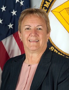 A light skinned woman with gray hair in a dark suit.