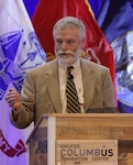 A light skinned man with gray hair and beard in a light business suit.