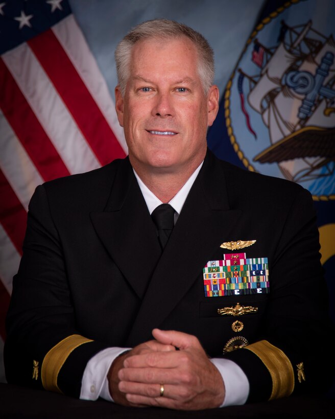 A light skinned man with gray hair in a dark Navy dress uniform.