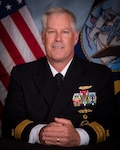 A light skinned man with gray hair in a dark Navy dress uniform.